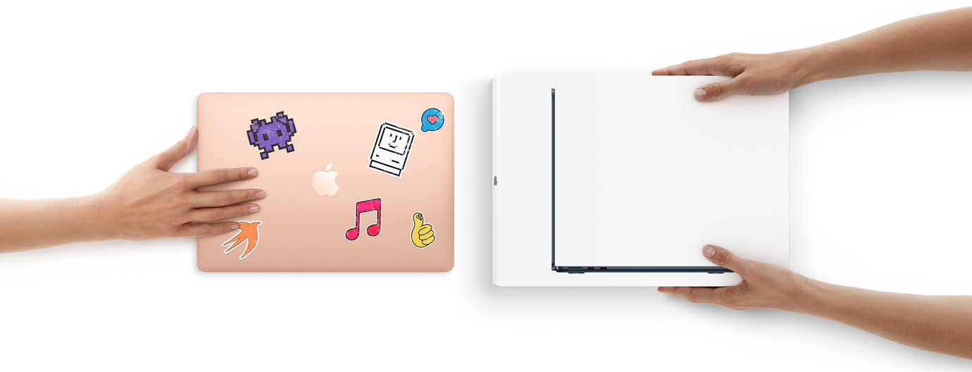 Une main pousse un MacBook couvert d’autocollants vers deux mains qui tiennent un nouveau MacBook dans son emballage.