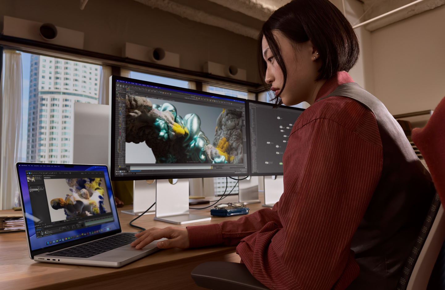 Osoba u uredskom okruženju radi na MacBook prijenosniku povezanom sa zaslonom Studio Display XDR putem priključka Thunderbolt 5