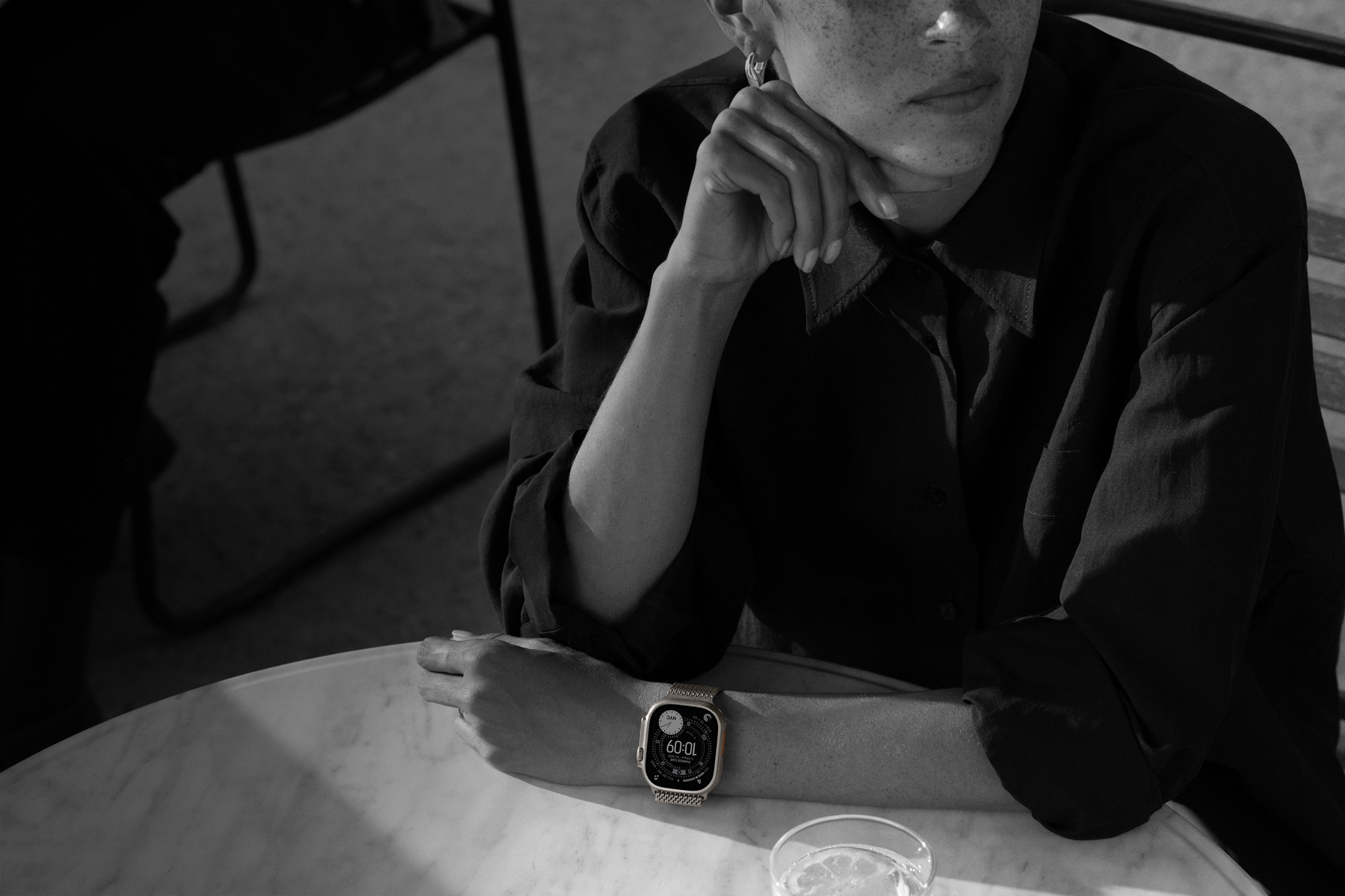Persona pie vakariņu galda ar Apple Watch Ultra 3 uz rokas
