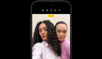 iPhone 18 Pro in Black, front-facing, showcasing two people with face tracking feature, demonstrates the Center stage front camera feature