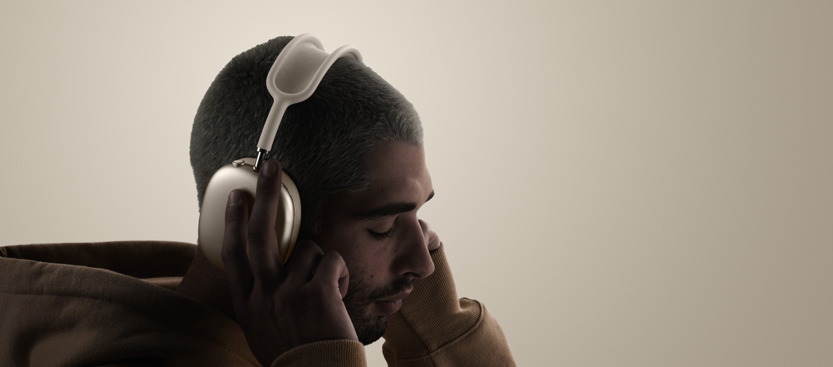 Zijkant van iemand met AirPods Max 2 koptelefoon, die de oorkussens aanraakt