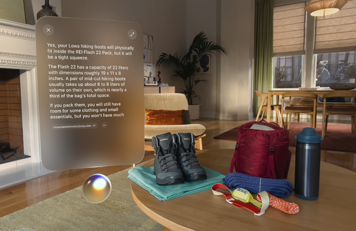 Vue de l’Apple Vision Pro, une conversation avec Siri pour savoir si des chaussures de randonnée rentrent dans un sac à dos apparaît au-dessus de Siri et à gauche d’une paire de chaussures de randonnée et d’autres équipements de plein air