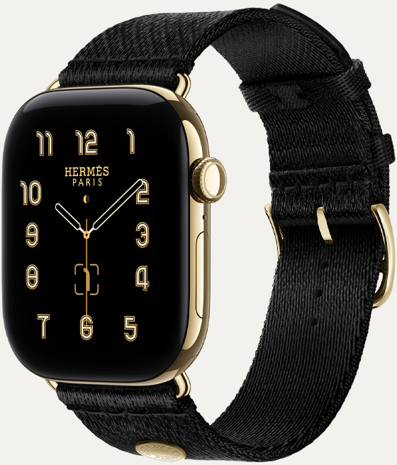 Apple Watch Hermès Series 12，展示 Clou de Selle 指針錶面 (時針、分針和秒針，複雜功能：月相、日期)，耀金色鈦金屬錶殼，配搭 Noir 黑色 Satin Clou de Selle 錶帶，採用順滑的黑色緞面織製，配搭與錶殼相同的耀金色金屬配件，機身右側有數碼錶冠和側邊按鈕