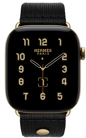 Apple Watch Hermès Series 12, esfera analógica Clou de Selle (aguja horaria, minutero y segundero, complicaciones: fase lunar, fecha), caja de titanio, color oro brillante, lateral derecho, Digital Crown, botón lateral, con la correa Clou de Selle Satin, color Noir, en suave tejido de satén negro con componentes en oro brillante a juego con la caja del reloj