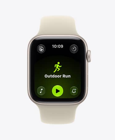 Apple Watch SE 3, hliníkové pouzdro, hvězdně bílá barva, na displeji aplikace Cvičení (běh venku), na pravém boku korunka Digital Crown, sportovní řemínek, písková (světle béžová) barva