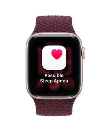 Apple Watch SE 3, na displeji upozornění na možný výskyt spánkové apnoe, hliníkové pouzdro, hvězdně bílá barva, na pravém boku korunka Digital Crown, pletený provlékací sportovní řemínek, burgundsky červená barva