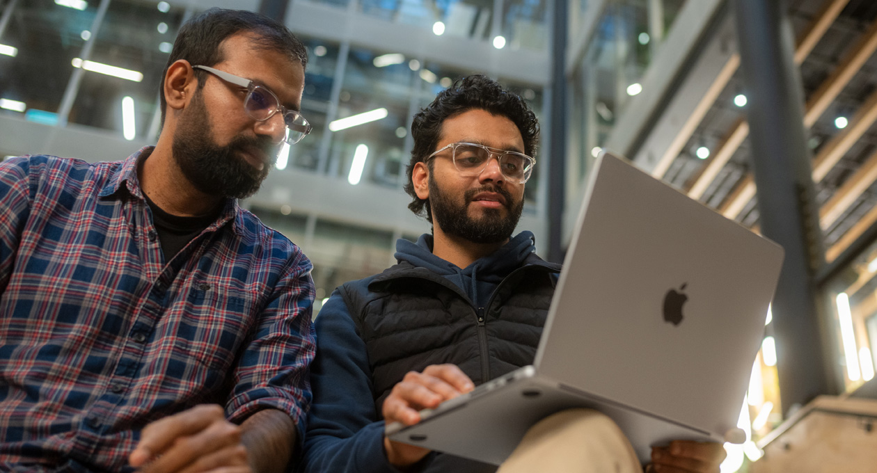 Två män med glasögon tittar på en MacBook Pro