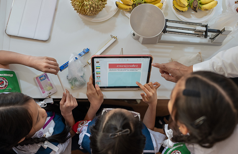 三名小學生圍在 iPad 前面為科學課
的專案簡報進行協作。
