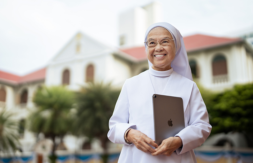 校長 Sister Françoise Jiranonda 拿著 iPad 站在校園外。