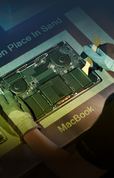 Hände in Handschuhen zerlegen ein MacBook, innere Komponenten sind sichtbar