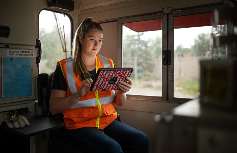 鉄道員が停車中の列車の車内に座り、iPadを見ている