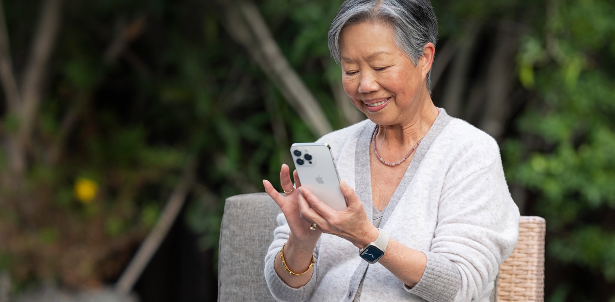 椅子に座ってiPhoneを見ている年配の女性