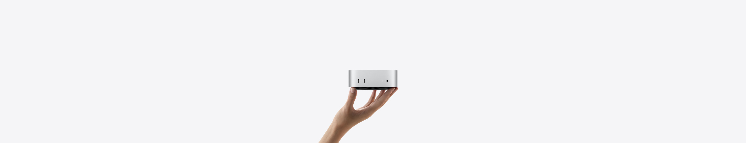 Vista frontal de una Mac mini sobre las puntas de los dedos de una mano estirada, con dos puertos Thunderbolt, luz indicadora de estado y entrada para audífonos, base cónica negra en la parte inferior, superficie plana en la parte superior, lados redondeados, bordes rectos, color plata