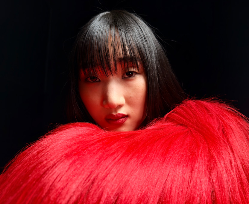 Primer plano de una mujer con una blusa de plumas rojo brillante que muestra las capacidades fotográficas en superalta resolución del iPhone 17 Pro