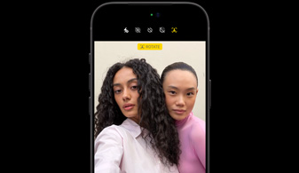 Vooraanzicht van iPhone 18 Pro in Zwart, op het scherm zijn twee mensen te zien met de feature gezichtstracking, demo van de feature Middelpunt van de camera aan de voorkant