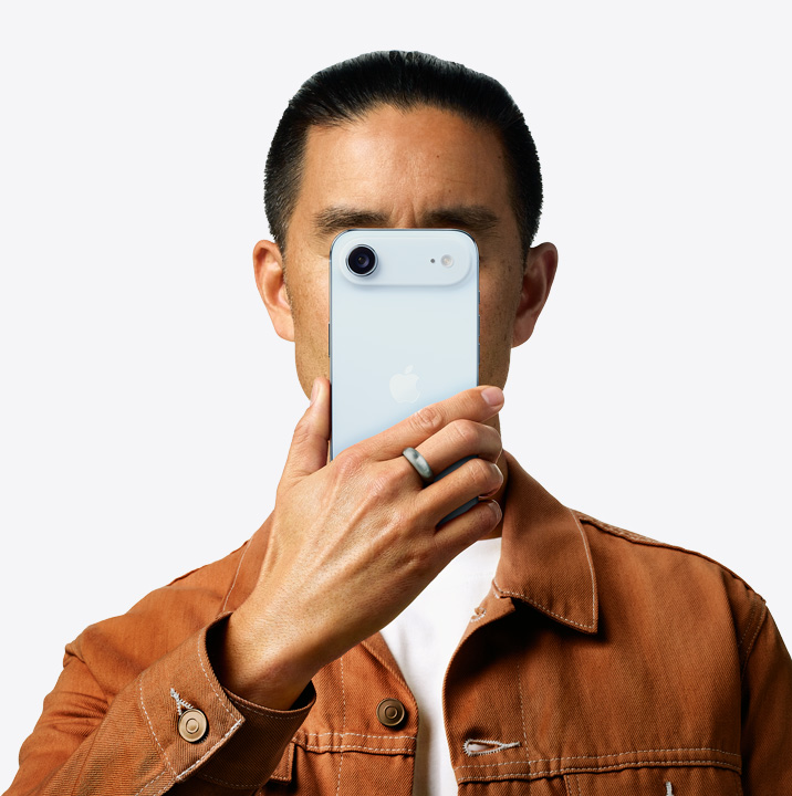 Person holding iPhone Air in sky blue finish in front of his face showing back exterior, dual camera system on left top corner