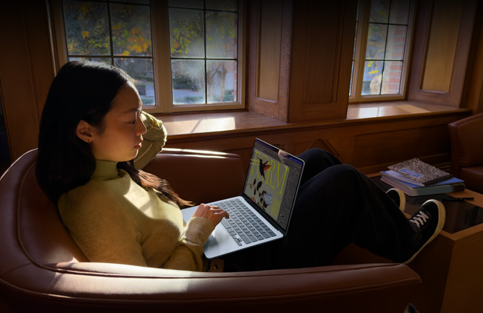 Eine Person auf einem Stuhl arbeitet mit einem MacBook Air